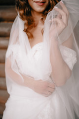 Fototapeta na wymiar Bride in a white dress with tender freckled hands. Female hands with a wedding ring. Shiny white beautiful dress. Detail of a bride dress closeup.