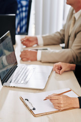 Businesswoman taking notes when attending meeting with colleagues and discussing important issues