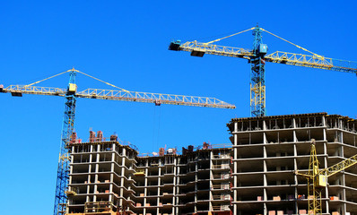 Concrete building under construction. Construction site. Two tower cranes near building.