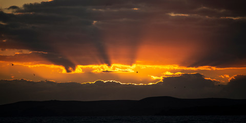 Rays of the sun peeking through dark clouds at sunrise. Illustrating the concept that Hope is on the horizon.