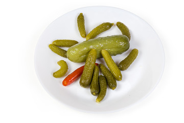 Pickled gherkins and ordinary cucumber on the white saucer