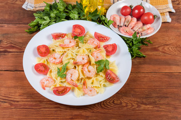 Farfalle pasta with shrimp tails and tomatoes against the ingredients