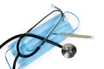 Stethoscope and clinical thermometer on disposable medical mask, top view