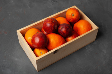 Bloody oranges in wooden box on dark concrete background top view. 