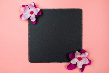 Black square with purple and white flowers on a pastel pink background