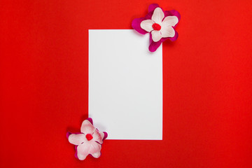 Purple and white flowers with white blank paper on a red background