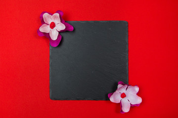Black square with purple and white flowers on a red background