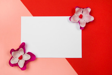 Purple and white flowers with white blank paper on a pastel orange and red background