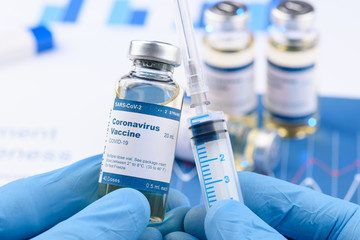 Coronavirus COVID-19 vaccine vial and injection syringe in scientist hands concept. Research for...