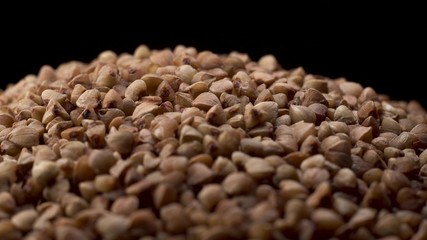 Nice cinematic footage of buckwheat slide spinning on black background. Buckwheat - the concept of proper and healthy food.