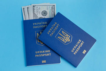 100 dollars banknote inside Ukrainian passport one passport lies next to a blue background close-up traveling business