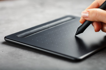 Graphic tablet with a pen in the hands of the designer, close-up. Gadget for creativity and work