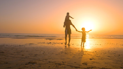 Fototapeta premium Father with kids playing in the beach at sunset