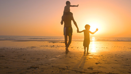 Fototapeta premium Father with kids playing in the beach at sunset