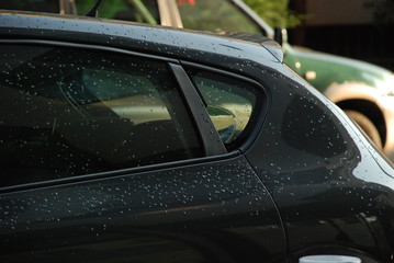 A shiny car covered with rain drops