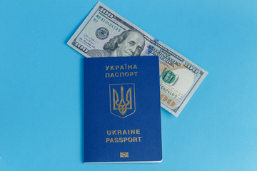100 dollars banknote inside one Ukrainian foreign passport on a blue background close-up traveling business