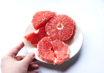 
sliced ​​red grapefruit on a white plate on a white background