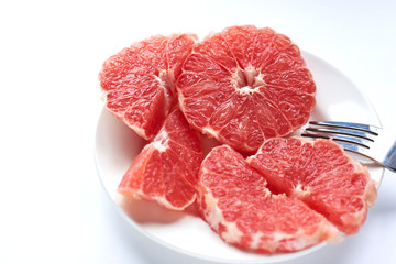 sliced ​​red grapefruit on a white plate on a white background