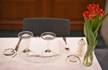an empty table in a cafe on the table is glassware and a vase with red flowers