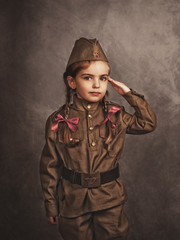 A child in military retro uniform salutes