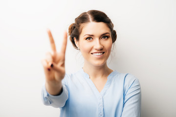 A woman shows a gesture of victory. Isolated on a white background