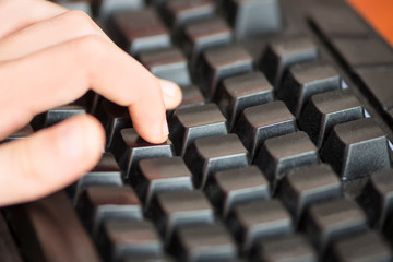 finger of the hand presses a computer keyboard key close up, send message, game, communication