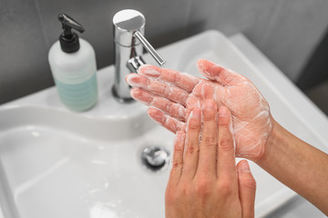 Washing hands rubbing soap in palm lathering up foam bubbles for corona virus COVID-19 prevention,...