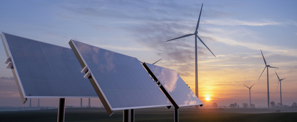 clean energy concept, photovoltaic panels and wind turbines in the light of the rising sun