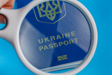 Magnifying glass shows biometric Ukrainian passport is inscribed Ukrainian passport on a blue background