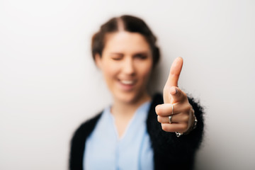 Woman shoots from an imaginary gun at the camera, covering one eye, focus on the hand. Isolated on a white background