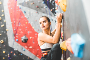 Sportswoman climber moving up on steep rock, climbing on artificial wall indoors. Extreme sports and bouldering concept