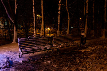 Yaroslavl, street Red Exit / Evening winter park in Yaroslavl. View at the bench with emblem of the Yaroslavl.