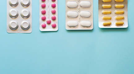 Layout of tablets and capsules on a plain blue background