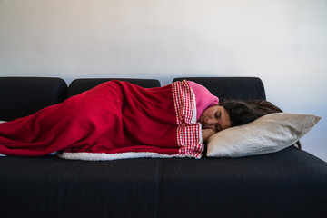 Woman with long hair sleeping in a sofa with a red wool blanket