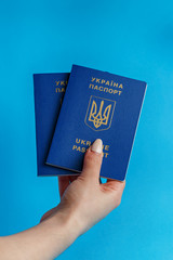 2 passports Ukraine in the hand of a girl with manicure on a blue background