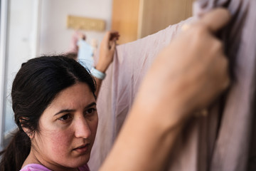 Serious expression of a woman hanging up washed sheets