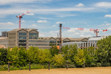 Bacalan district in Bordeaux France with white and red cranes above dwellings and buildings seem from the other bank of the Garonne River