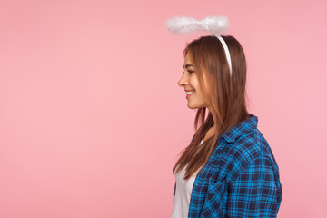 Portrait of positive beautiful angelic girl with nimbus over head smiling joyfully and looking at...