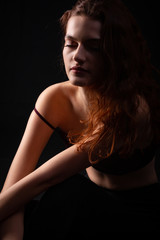 Fototapeta na wymiar Portrait of a young curly girl in a dark studio