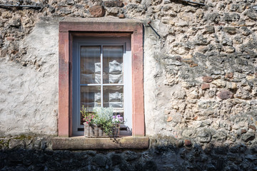 An old window on a wall with a basket of flowers