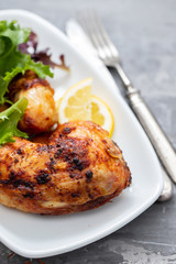 grilled chicken with lemon and salad on white dish