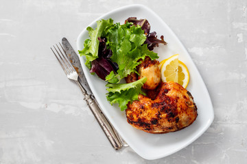 grilled chicken with lemon and salad on white dish
