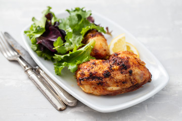 grilled chicken with lemon and salad on white dish