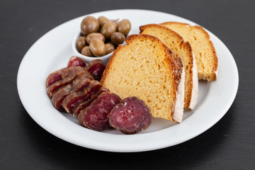 corn bread with smoked sausage and olives on white plate