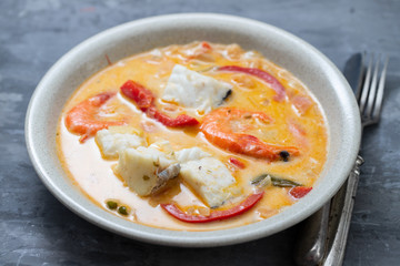 fish with shrimps and pepper in sauce in the dish on ceramic background