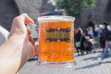 Fototapeta premium OSAKA, JAPAN - Oct 24, 2017: Hand holding glass with Butter beer in Wizarding World of Harry Potter at Universal Studios Japan. Universal Studios Japan famous amusement park, Osaka city.