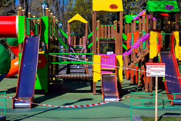 Fototapeta na wymiar Children's playground closed and wrapped in alarm caution tape for global coronavirus quarantine