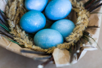 Easter holiday decorations, background. Basket with painted blue eggs, with bars, branches, flowers. Religion.