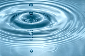 Naklejka na ściany i meble Water drops splash in a glass blue colored