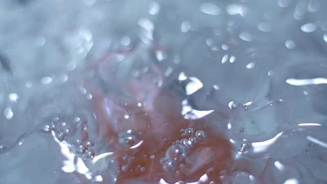 Shot of orange bottle falling into cooler container under the ice cubes on slow motion